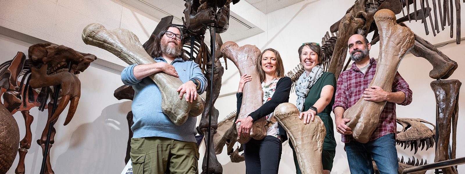 Geology staff pose with replicas of large bones.