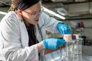 A woman wearing a lab coat measures ice cream.