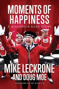 The book cover 'Moments of Happiness' by Mike Leckrone and Doug Moe features an image of Leckrone directing the UW Marching Band, smiling broadly.