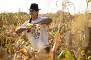 Indigenous man stands in corn field holding ear of corn