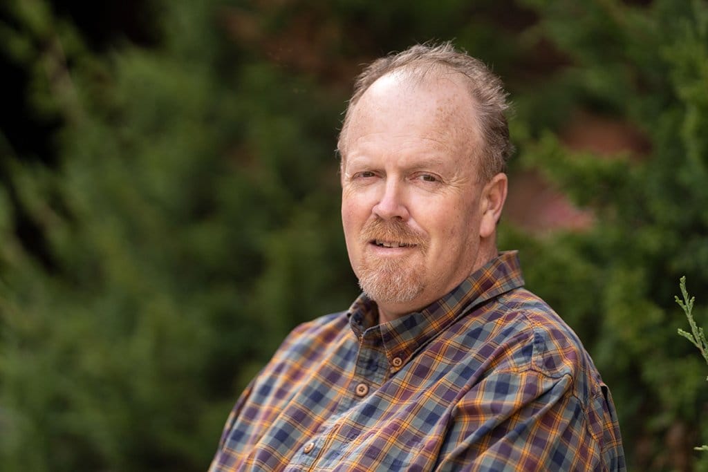 Headshot of Gary Grosklaus outdoors, wearing a plaid shirt.