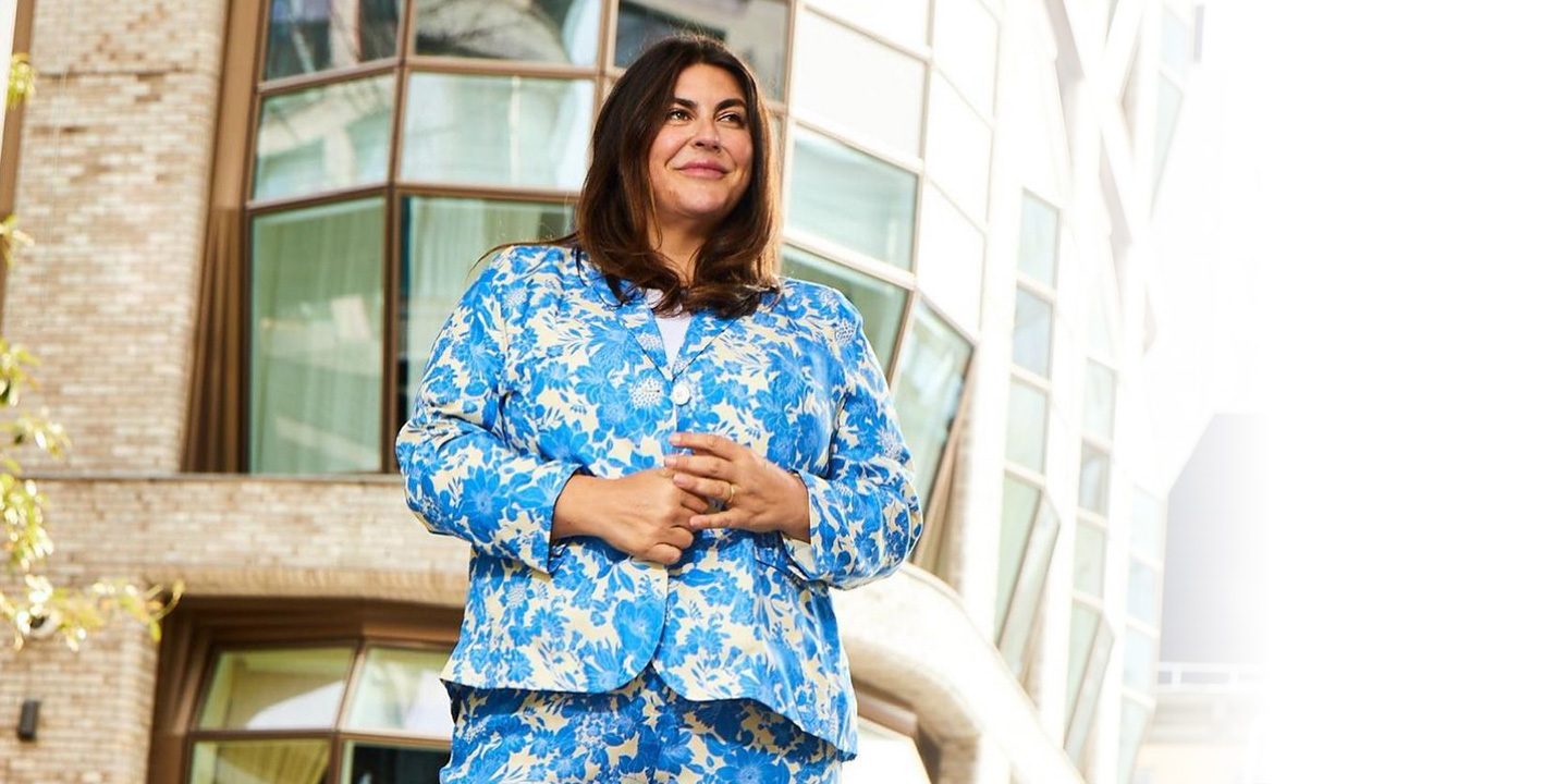 Katie Sturino standing in an urban setting wearing a colorful pantsuit.