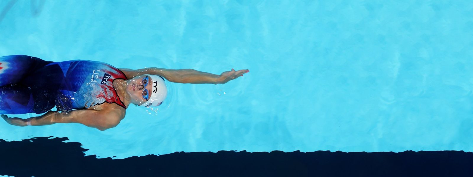 Image of Phoebe Bacon swimming backstroke, and wearing a USA technical suit.