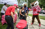 People wearing Badger gear and name tags interact with a friendly Bucky Badger mascot