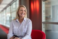 Photograph of Alisa Robertson, sitting in a red chair.