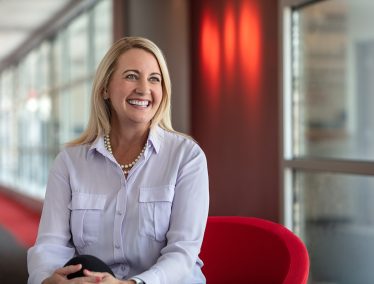 Photograph of Alisa Robertson, sitting in a red chair.