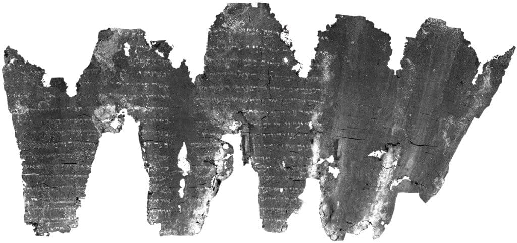 A charred scroll, virtually flattened, with visible characters on it.