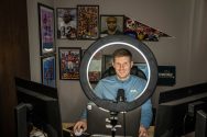 Nick Whalen sits in front of a computer monitor illuminated by a large ring light