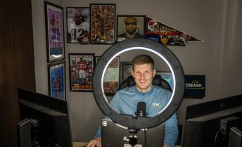 Nick Whalen sits in front of a computer monitor illuminated by a large ring light