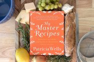 Photo of Patricia Wells' book, "Master Recipes" surrounded by herbs, an onion, lemon, garlic, grapes and a baguette