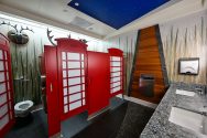 A uniquely designed restroom with red British telephone booth-style stalls, a starry night ceiling, and nature-themed decor.