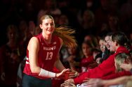 Sarah Franklin, in volleyball uniform, high-fives people on the side of the volleyball court.