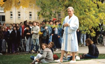 A group of people gathered outdoors on Bascon Hill, with Rodney Dangerfield (as character Thornton Melon) in a bathrobe and slippers among casually dressed students and actors.