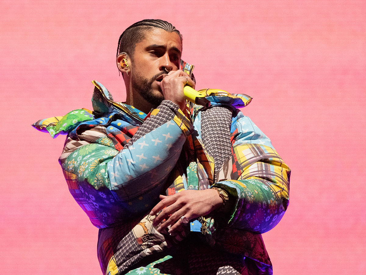 Musician Bad Bunny wearing a colorful jacket and holding a microphone.