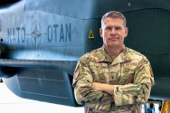 Brigadier General Andrew Clark stands in front of a military aircraft.