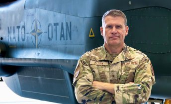 Brigadier General Andrew Clark stands in front of a military aircraft.