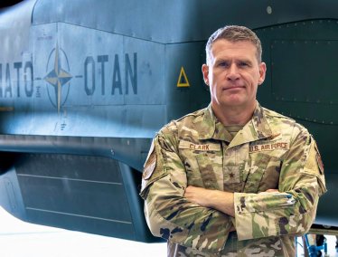 Brigadier General Andrew Clark stands in front of a military aircraft.