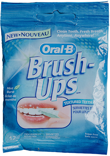 A blue package of Oral-B Brush-Ups featuring promotional text about mint flavor and on-the-go teeth cleaning, with an image of a person using a textured wipe on their teeth.