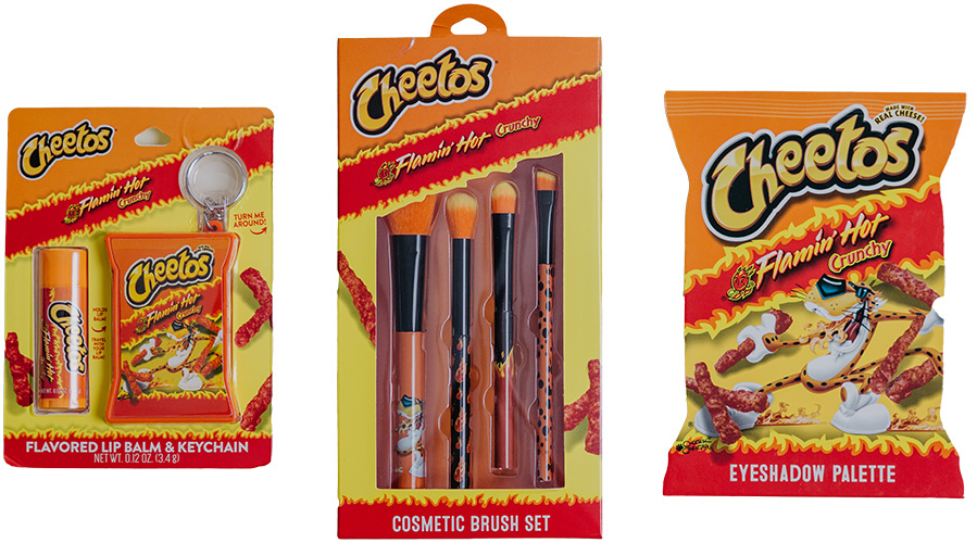 Three Cheetos-branded cosmetic products themed around Flamin' Hot Crunchy Cheetos, including a flavored lip balm and keychain set, a cosmetic brush set, and an eyeshadow palette.