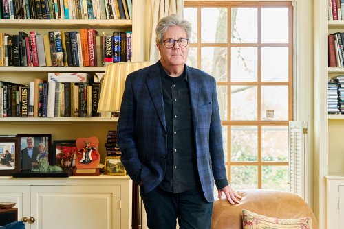 David Maraniss stands in a bright living room with bookshelves filled with books and CDs.
