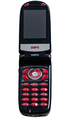 A black and red flip phone with the ESPN logo on the screen and Sanyo branding below, featuring a circular navigation pad and a keypad with multiple buttons.