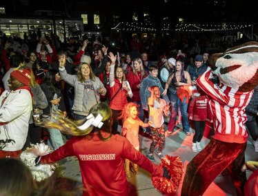 Badger fans decked out in red dance with Bucky Badger mascot