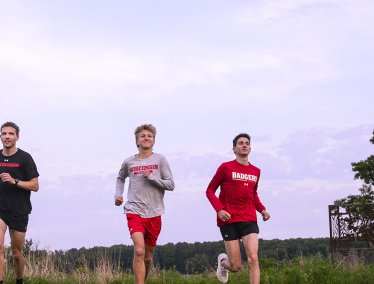 Rowen Ellensberg, Christian deVaal, and Bob Liking, members of the men’s cross country team, run in Curtis Prairie on a summer evening at the UW Arboretum at the University of Wisconsin–Madison