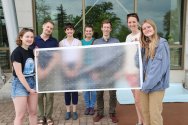 A group of smiling students pose holding a bird-safe window cover