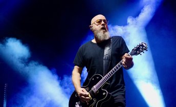 Steve Marker plays guitar against dramatic blue stage lights