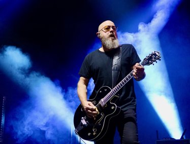 Steve Marker plays guitar against dramatic blue stage lights