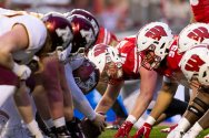The Badger and Gopher football teams line up at the line of scrimmage, crouched and ready for the snap.