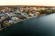Aerial view of a the UW-Madison campus with numerous buildings, green spaces, and a waterfront.