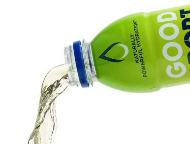 A green bottle labeled 'GOOD SPORT' with the phrase 'NATURALLY POWERFUL HYDRATION' is tilted, pouring clear liquid.