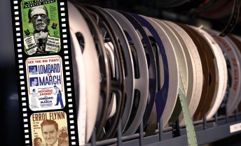 A shelf filled with colorful archival film reels, some with hanging strips.