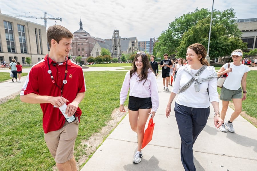 Tour guide Lucas Liske walks along a campus sidewalk with a group of people on campus.