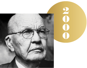Black and white headshot of Jack St. Clair Kilby with an overlapping gold circle representing a Nobel medal, with the year 2000 on it.