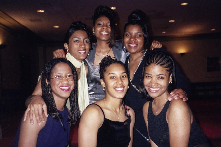 Group photograph of six women dressed in formal evening attire, posing closely together.