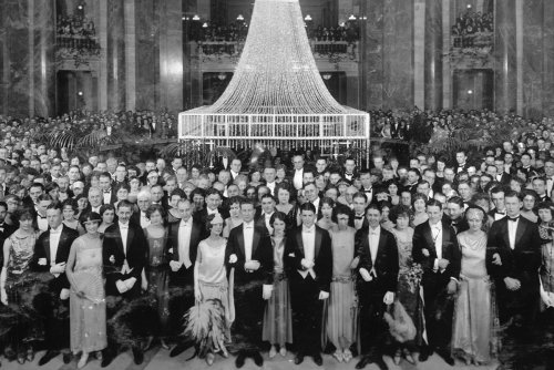 Black and white archival photo of a large crowd of elegantly dressed people poses in the Madison capitol building.