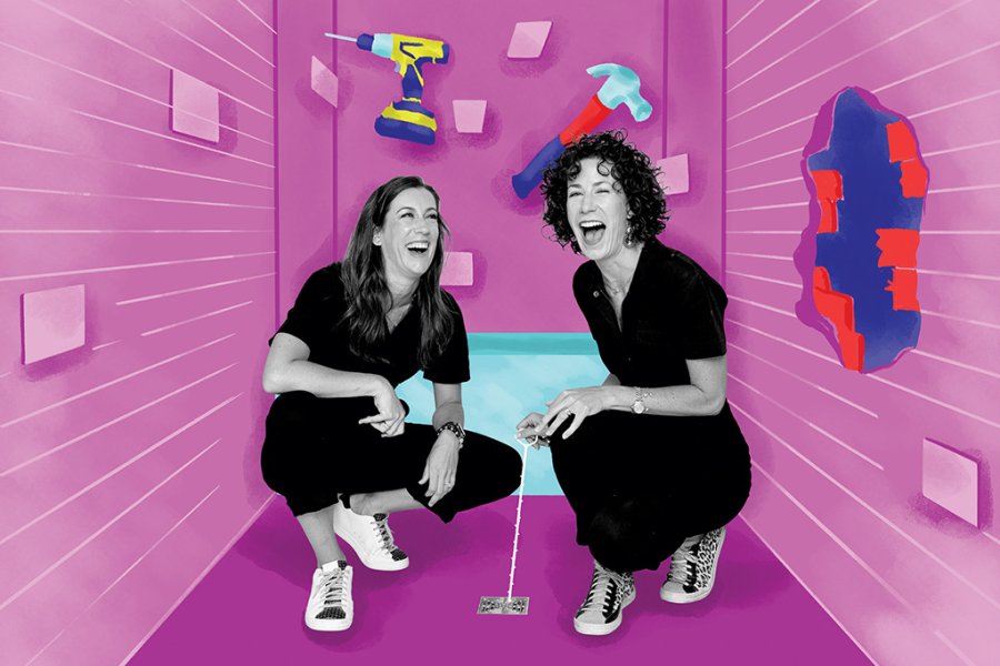 Two women crouch and laugh in a brightly colored, stylized room with illustrated tools on the walls and bold graphic design elements.