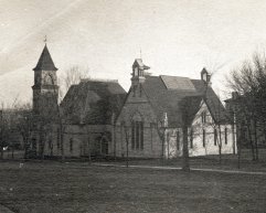A historic, sepia-toned photograph from 1890 showing the exterior of a large, stone music hall building with a prominent clock tower and Gothic-style architecture, surrounded by bare trees and an open lawn.