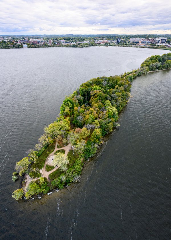 An aerial photograph of Picnic Point -- a narrow, tree-covered peninsula extending into Lake Mendota.