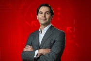 Portrait of Brad Chandler posing with crossed arms against a red graphic background featuring cryptocurrency logos and blockchain graphics.