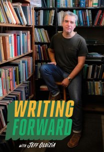 Jeff Oloizia sits on a wooden stool in a narrow aisle surrounded by floor-to-ceiling bookshelves filled with books with the name of his podcast, Writing Forward, overlaying the photo.